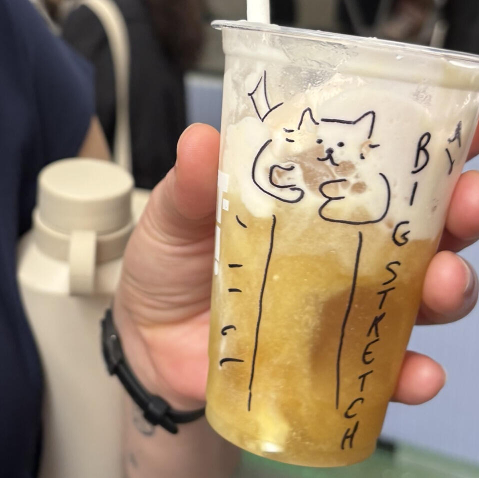 A close up shot of a plastic cup filled with an amber liquid mixing with a foamy cream substance