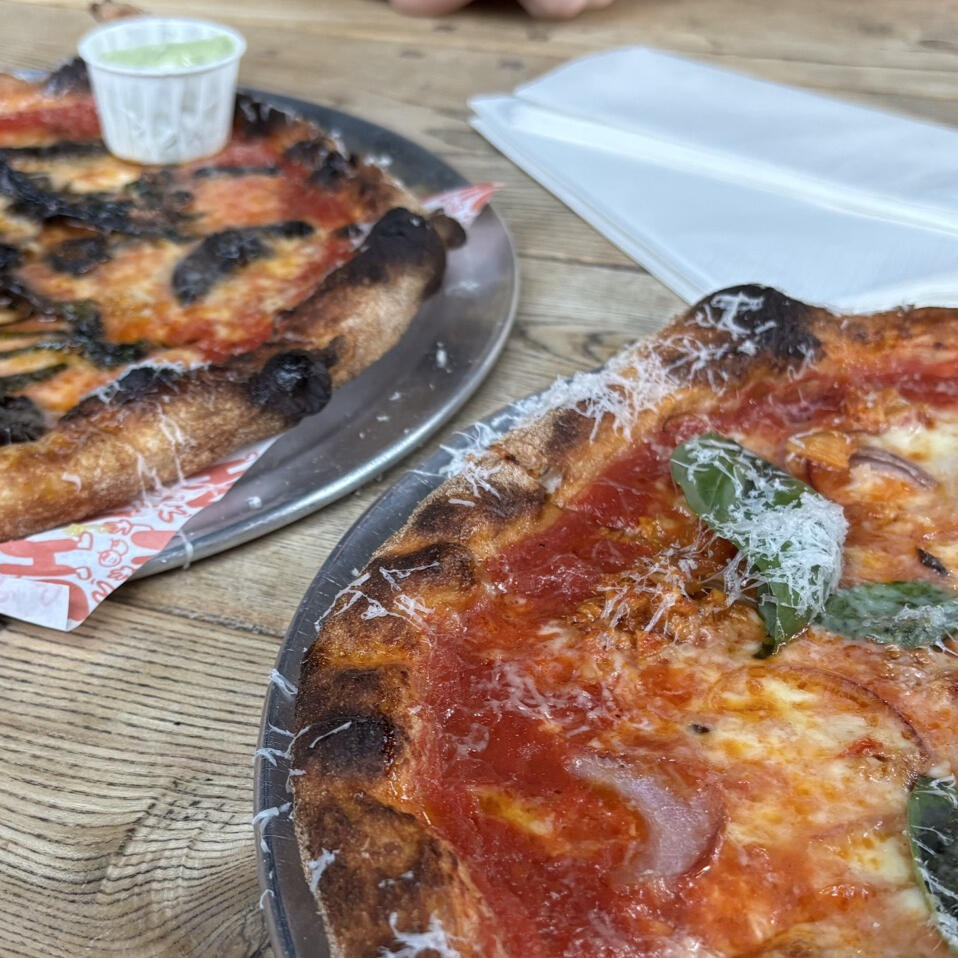 A close up shot of two pizzas on a wooden table